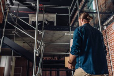 Yeni ofisin merdivenlerinin yanındaki kutuları tutan iş adamının düşük açılı görüntüsü