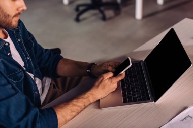 Masanın yanında akıllı telefon kullanan işadamının görüntüsü.