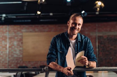 Neşeli iş adamı modern ofiste klasör tutuyor.