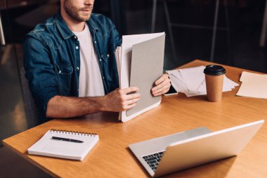 İş adamının elindeki dosyalar ve kağıt bardaklar masanın üstünde.