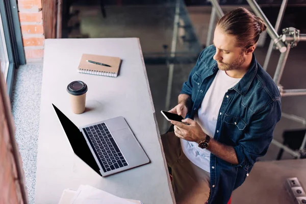 Wysoki Kąt Widzenia Biznesmena Pomocą Smartfona Pobliżu Laptopa Jednorazowego Kubka — Zdjęcie stockowe