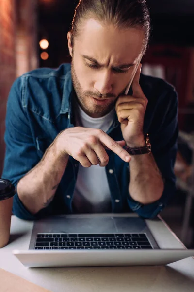 Biznesmen Rozmawiający Smartfonie Przy Papierowej Filiżance Wskazujący Palcem Laptopa — Zdjęcie stockowe