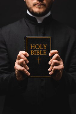 Rahibin elinde kutsal İncil 'in yazılı olduğu siyah bir kitap tutarken çekilmiş görüntüsü. 