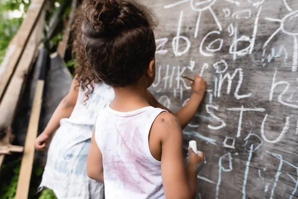 back view of poor african american kids near chalkboard