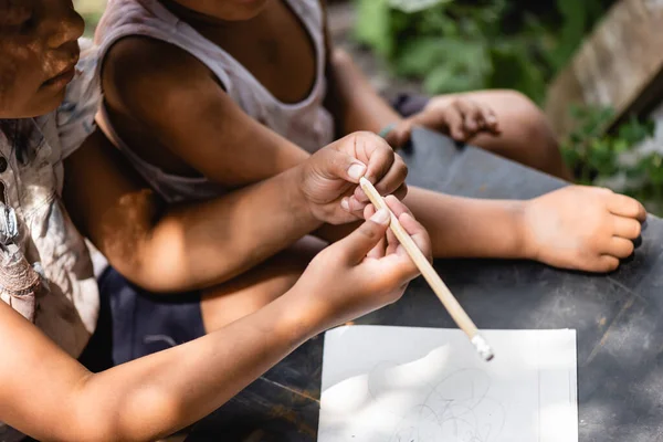 贫穷的非洲裔美国孩子把铅笔放在书桌上和孩子身边的剪影 — 图库照片