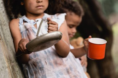 Selective focus of poor African american children begging alms on urban street  clipart