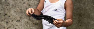 Fakir Afrikalı Amerikalı çocuğun panoramik mahsulü şehir caddesinde cüzdan taşıyor. 