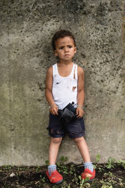 Endişeli Afro-Amerikan çocuk kirli giysiler içinde. Şehir caddesinde boş cüzdan taşıyor. 