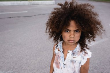 Zavallı Afro-Amerikan çocuğu. Dağınık suratlı. Şehir sokağındaki kameraya bakıyor. 