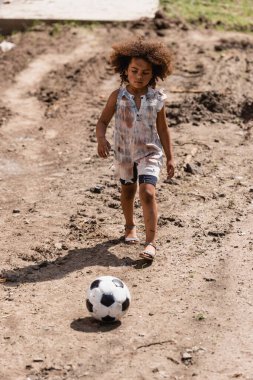 Kentsel sokakta futbol oynayan zavallı Afrikalı Amerikalı çocuğun seçici odak noktası 