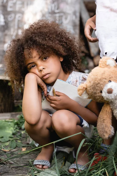 Chateado Pobre Garoto Afro Americano Segurando Notebook Perto Criança Com — Fotografia de Stock