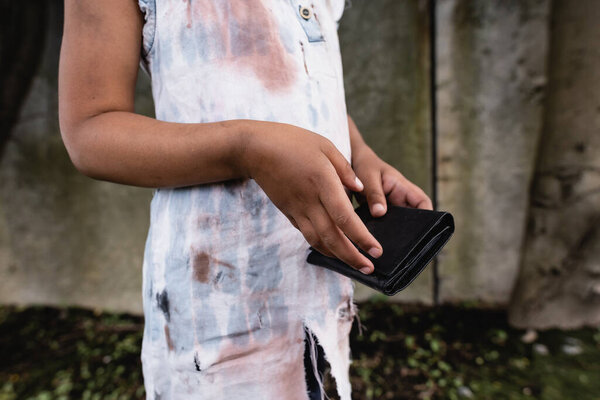 Обрезанный вид бедного африканского американского ребенка, держащего бумажник на городской улице 