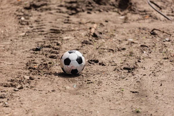 Dirty soccer ball on road on urban street 