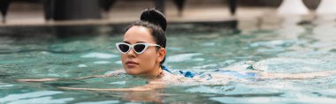 Güneş gözlüklü, havuzda yüzen çekici genç kadın konsepti 