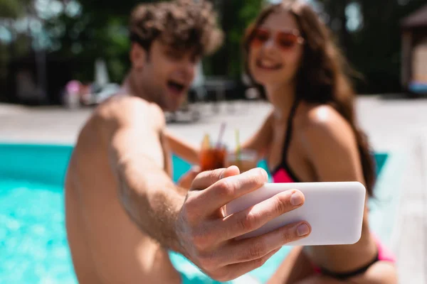 カクテルを飲みながらプールの近くで自撮りする幸せな男女の選択的焦点 — ストック写真