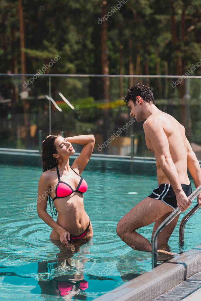 Hombre en bañador de pie junto a la piscina