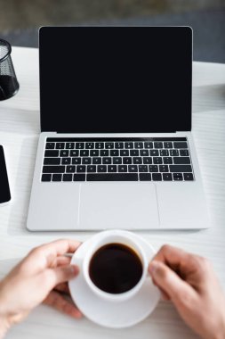 Bilgisayarın yanında elinde kahve fincanı tutan adamın boş ekranlı görüntüsü, online konsept kazanıyor.