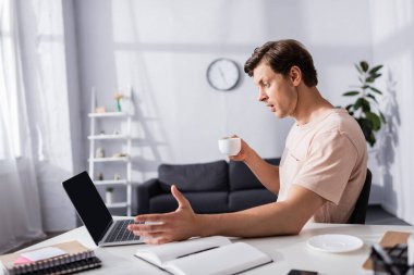 Evde bardak tutarken dizüstü bilgisayara bakıp online konsept kazanmanın seçici odak noktası