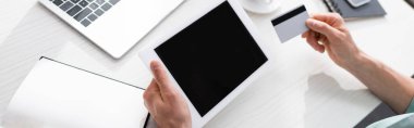Masada dijital tablet ve kredi kartı tutan adamın panoramik ürünü, online kazanç kavramı