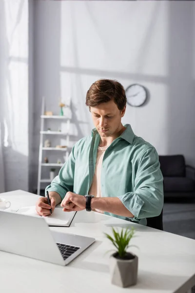 Enfoque Selectivo Escritura Freelancer Cuaderno Mirando Reloj Pulsera Cerca Computadora — Foto de Stock