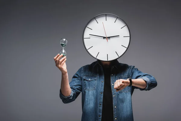 時計を頭に持つ男 グレーの背景に腕時計や砂時計 時間管理の概念 — ストック写真