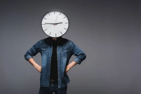 時計を頭に持っている男と灰色の背景に腰に手 時間管理の概念 — ストック写真