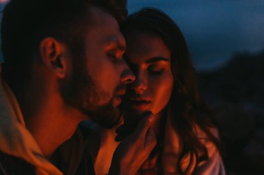 Geceleri sakallı bir adamın çekici bir kadına dokunuşunun seçici odağı.