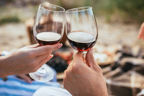 selective focus of couple clinking glasses with red wine 