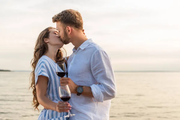 Pareja Besando Sosteniendo Vasos Con Vino Tinto Cerca Del Lago —  Fotos de Stock