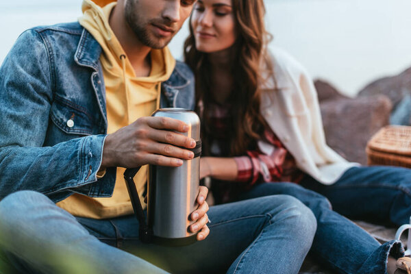 selective focus of bearded man holding thermos beautiful girlfriend 