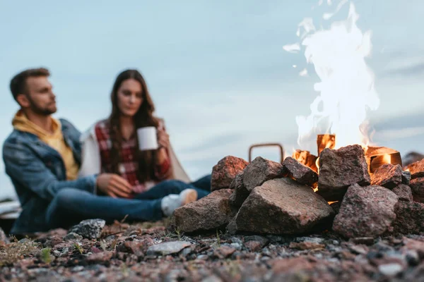 靠近坐在岩石上的夫妇燃烧篝火的选择性焦点 — 图库照片