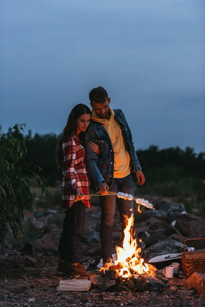 Pár Stojící Blízkosti Hořícího Táboráku Pečení Marshmallows Tyčinkách — Stock fotografie