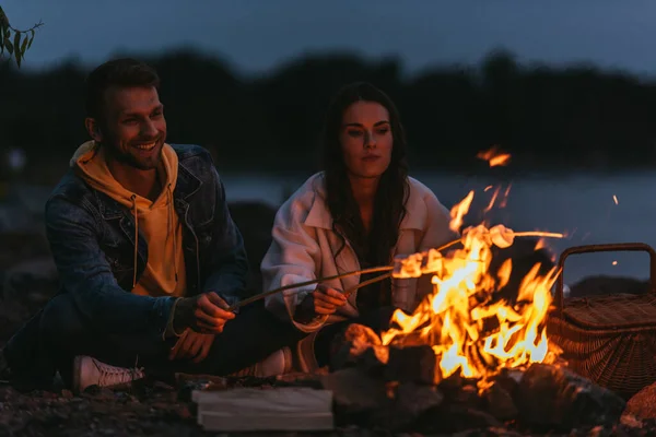 Fuoco Selettivo Coppia Felice Arrostendo Marshmallows Bastoni Vicino Falò Notte — Foto Stock