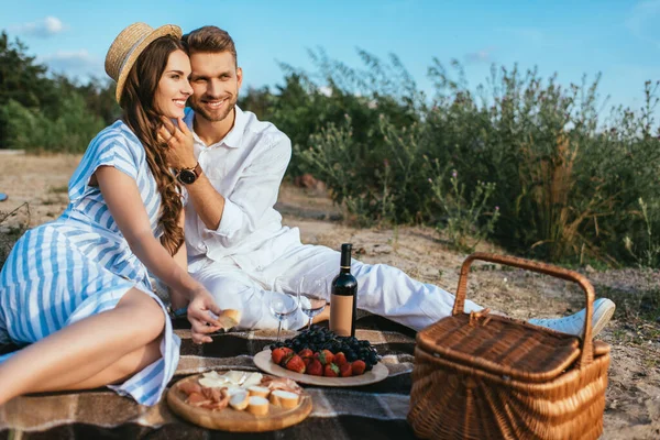 幸せなカップルがおいしい食べ物やワインとボトルの近くに座って — ストック写真
