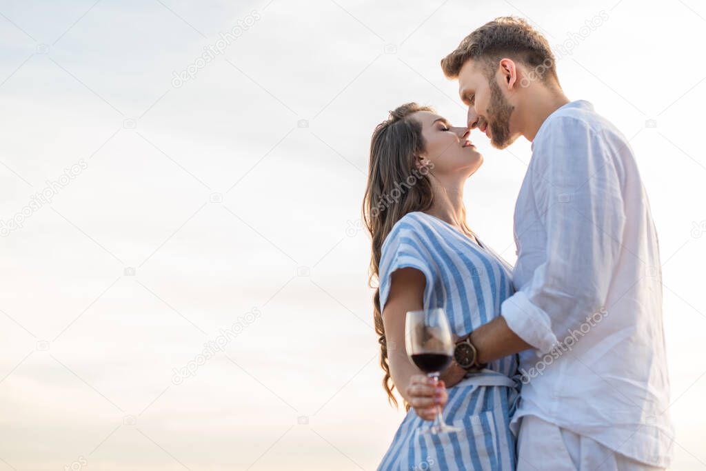 side view of happy woman holding glass with red wine near cheerful boyfriend 