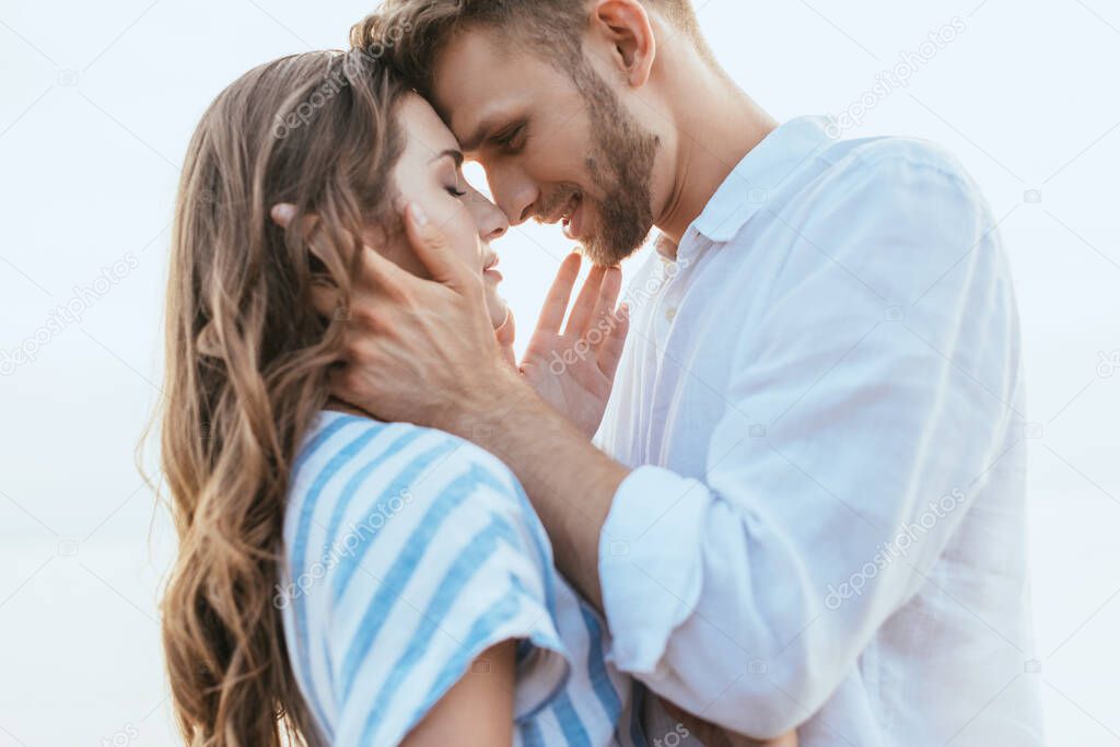 happy and bearded man touching face of beautiful girlfriend outside 