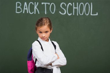 Okulun yakınındaki kameraya bakan şüpheci kız tahtaya yazı yazmış.