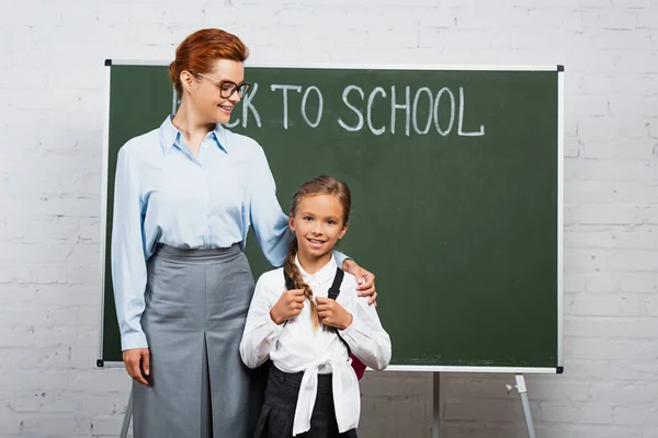 Glückliche Lehrerin Und Schülerin Stehen Neben Kreidetafel Mit Schulbuchstaben — Stockfoto