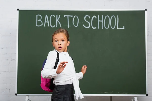 Chockad Skolflicka Med Ryggsäck Tittar Kameran Nära Tavlan Med Tillbaka — Stockfoto