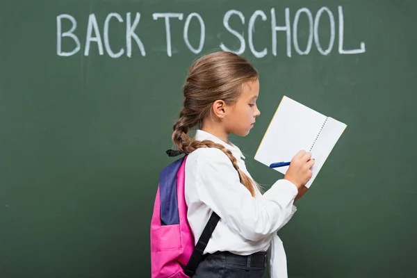 Schülerin Mit Rucksack Schreibt Kopierbuch Neben Kreidetafel Mit Schuleinschreibung — Stockfoto