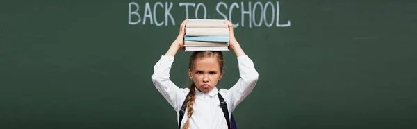 Cultivo Panorámico Colegiala Disgustada Sosteniendo Pila Libros Por Encima Cabeza — Foto de Stock