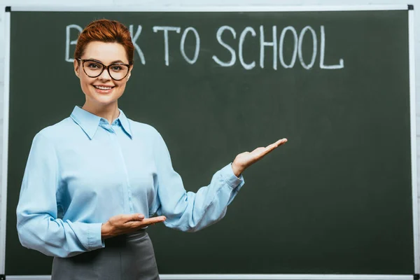 Lächelnder Lehrer Zeigt Mit Händen Der Nähe Von Kreidetafeln Mit — Stockfoto