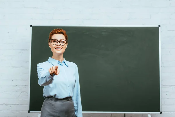 Smiling Teacher Looking Camera Pointing Finger Chalkboard — Stock Photo, Image