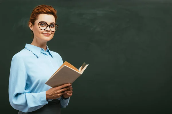 Feliz Hermosa Maestra Anteojos Sosteniendo Libro Abierto Mientras Está Pie —  Fotos de Stock