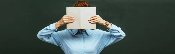 Lehrer Verdeckt Gesicht Mit Aufgeschlagenem Buch Während Neben Tafel Steht — Stockfoto