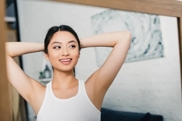선택적 초점을 집에서 거울을 아시아인 여인에게 미소짓는 — 스톡 사진