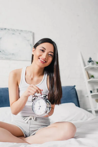 Hermosa Mujer Asiática Sonriendo Cámara Mientras Sostiene Reloj Despertador Cama —  Fotos de Stock