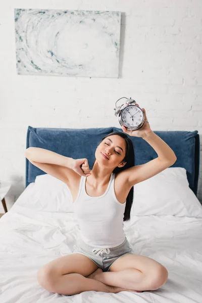 Young Asian Woman Holding Alarm Clock Stretching Bed Morning — Stock Photo, Image