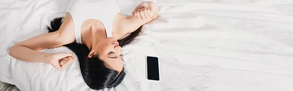 Panoramic Shot Gadis Asia Peregangan Dekat Smartphone Tempat Tidur Pagi — Stok Foto