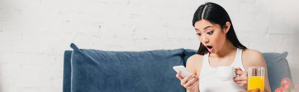 Foto Panorámica Mujer Asiática Conmocionada Usando Teléfono Inteligente Sosteniendo Taza — Foto de Stock